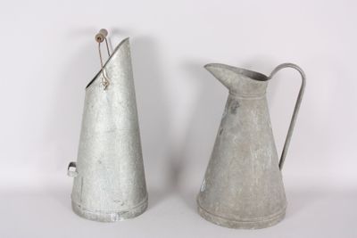 two metal pitchers sitting next to each other on a table