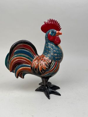 une figurine de coq aux couleurs vives posée sur une surface blanche