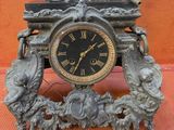 a clock with a statue on top of it on a table