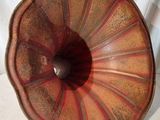 un vase rouge et marron posé sur une surface blanche