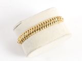un gros plan d'un bracelet à chaîne dorée sur une bague blanche