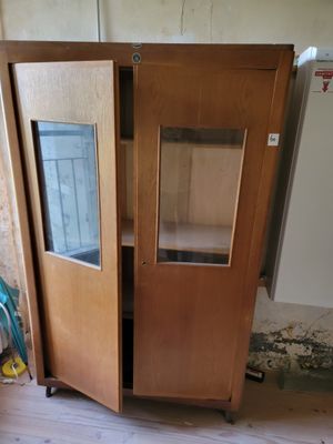 a wooden cabinet with a glass door in the middle of a room
