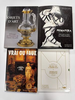trois livres posés sur une table blanche, sur laquelle se trouve un vase doré