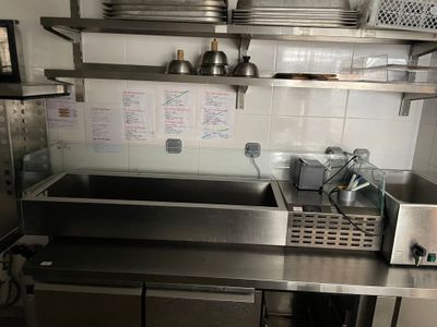 un évier en acier inoxydable dans une cuisine, avec des étagères au-dessus