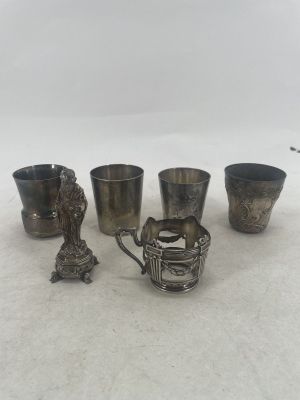 four silver cups and spoons sitting next to each other on a white surface