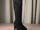 black sued high heeled boots on a wooden table