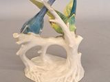 two figurines of birds sitting on a tree branch