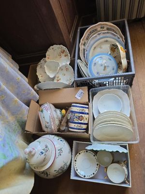 beaucoup d'assiettes et de tasses dans des cartons posés par terre
