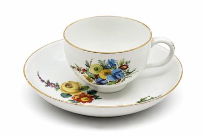 une tasse et une soucoupe sur une soucoupe sur une surface blanche