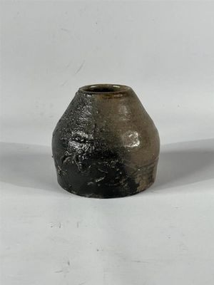 un vase noir et blanc posé sur une surface blanche