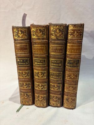 cinq vieux livres sont empilés les uns sur les autres sur une surface blanche