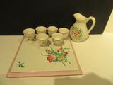 cinq tasses et un pichet posés sur un plateau posé sur une table