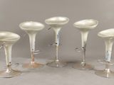 quatre tabourets en plastique blanc placés les uns à côté des autres sur une table