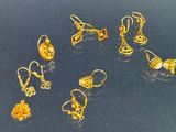 Plusieurs paires de boucles d'oreilles en or sont exposées sur un fond noir