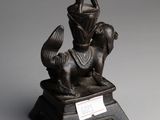 a bronze statue of a woman sitting on top of a dog