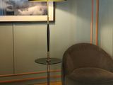 a chair and a lamp in a room with a picture on the wall
