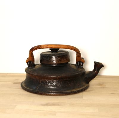 une bouilloire à thé noire posée sur une table en bois