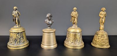quatre clochettes en laiton antique sont alignées sur une surface noire