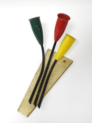 trois gobelets en plastique de couleurs différentes posés sur un morceau de bois