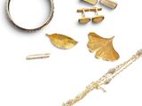 un bracelet en or, une bague et d'autres bijoux posés sur un fond blanc