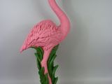 un flamant rose posé sur un socle blanc