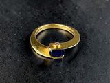an image of a gold ring with a blue stone in it