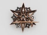 an image of a metal star broochle on a white surface