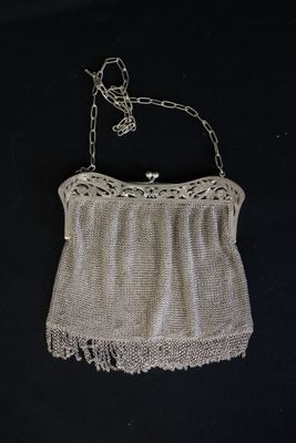 an old purse with a chain attached to it on a black background