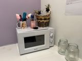 a microwave on a counter with a basket of flowers on top of it