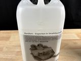 une bouteille de liquide posée sur une table à côté d'une autre bouteille de liquide