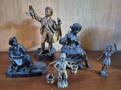 five bronze figurines of people sitting on a table
