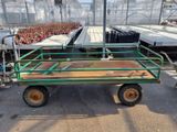 un chariot vert sur lequel est posée une table en bois, dans une serre