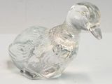 figurine de canard en verre transparent posée sur une surface blanche