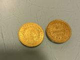 two gold coins sitting next to each other on top of a table
