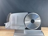 a silver electric slicer sitting on a wooden table