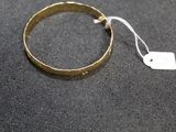 a close up of a gold bracelet with a tag on it