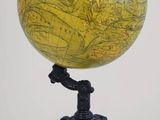globe jaune et noir posé sur un trépied, sur fond blanc