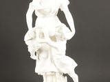 une statue blanche représentant une femme tenant un panier de fleurs