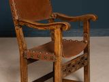 an old wooden chair with a brown leather seat on a white floor