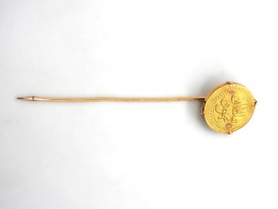 an old gold coin on a wooden stick on a white surface