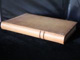 un livre en cuir marron posé sur un canapé noir