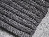 close up of a black and grey rug on a concrete floor