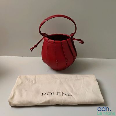 un petit sac à main rouge posé sur une table à côté d'un sac