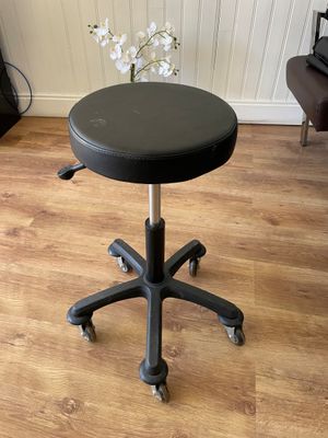 a black stool with wheels and a flower in a vase