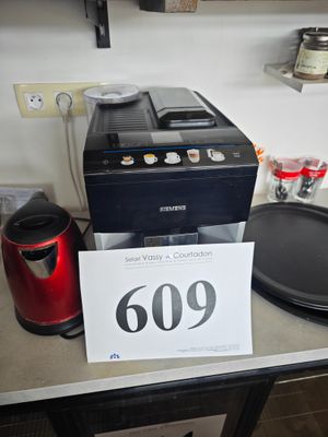 une cafetière posée sur un plan de travail, à côté d'un panneau