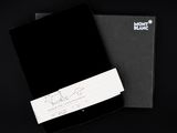 le cahier noir est ouvert sur une surface noire, à côté d'un bloc-notes