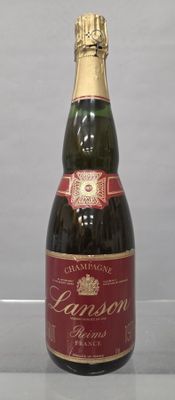 Des bouteilles de vin sont posées sur une table devant un fond gris.