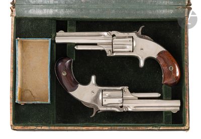 two silver revolvers in a green box with a leather case