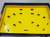 someone is holding a yellow box with holes cut out of it