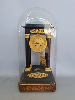 une horloge placée sous un dôme en verre, posée sur une table